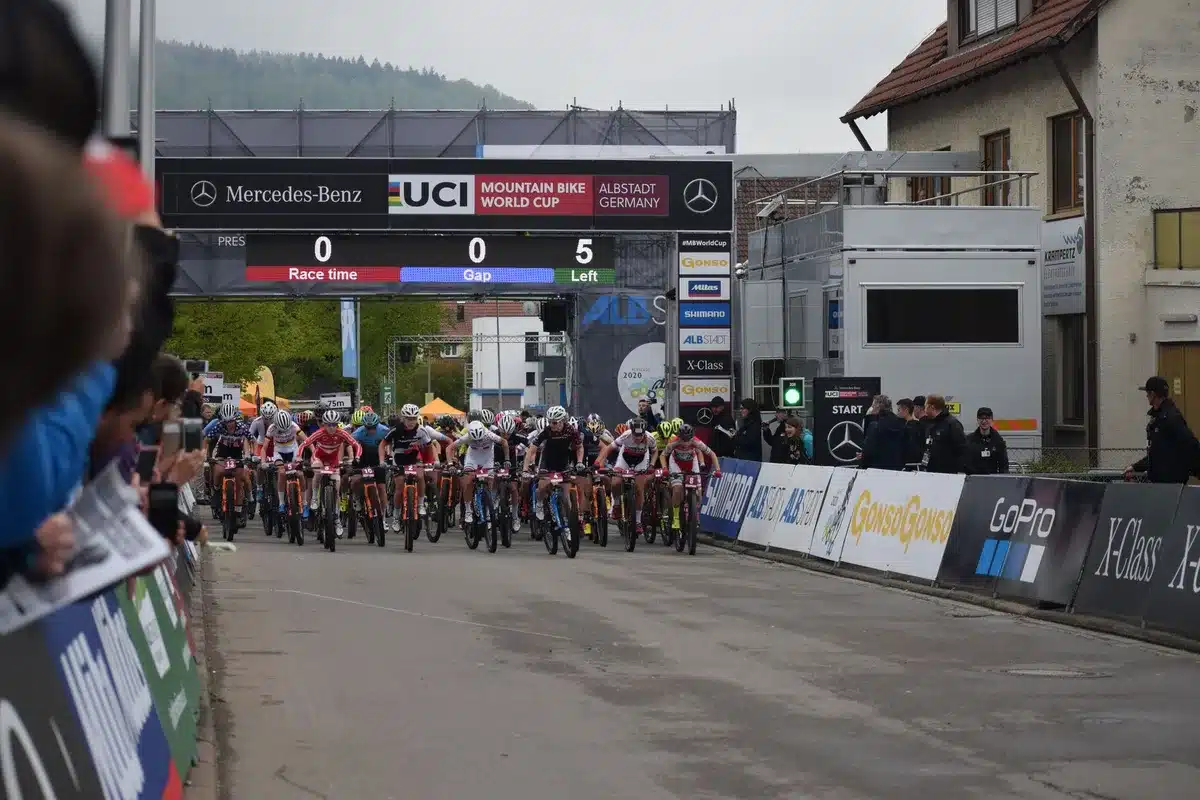 Salida de una carrera de MTB en formato XCC con ciclistas compitiendo en un circuito técnico