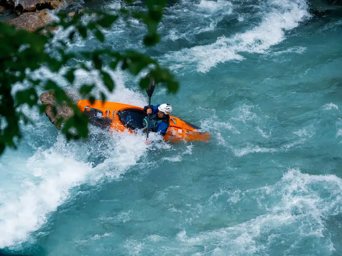 Detalle de un palista pasando una puerta en un recorrido de slalom en aguas bravas.