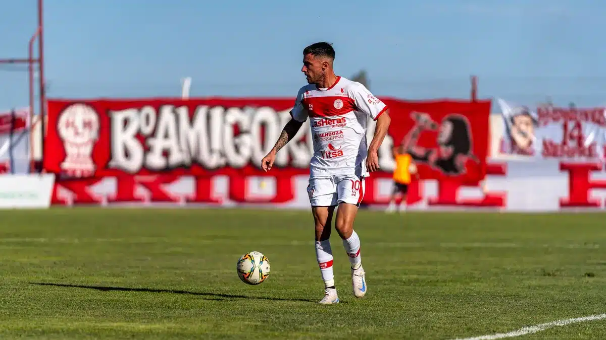 Joven futbolista sosteniendo documentación de contrato en un moderno estadio de fútbol.