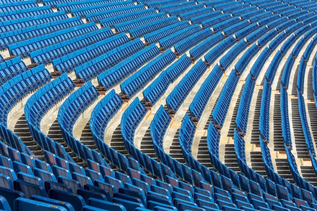 Estadio bajo la lluvia con balones y aficionados anónimos en las gradas