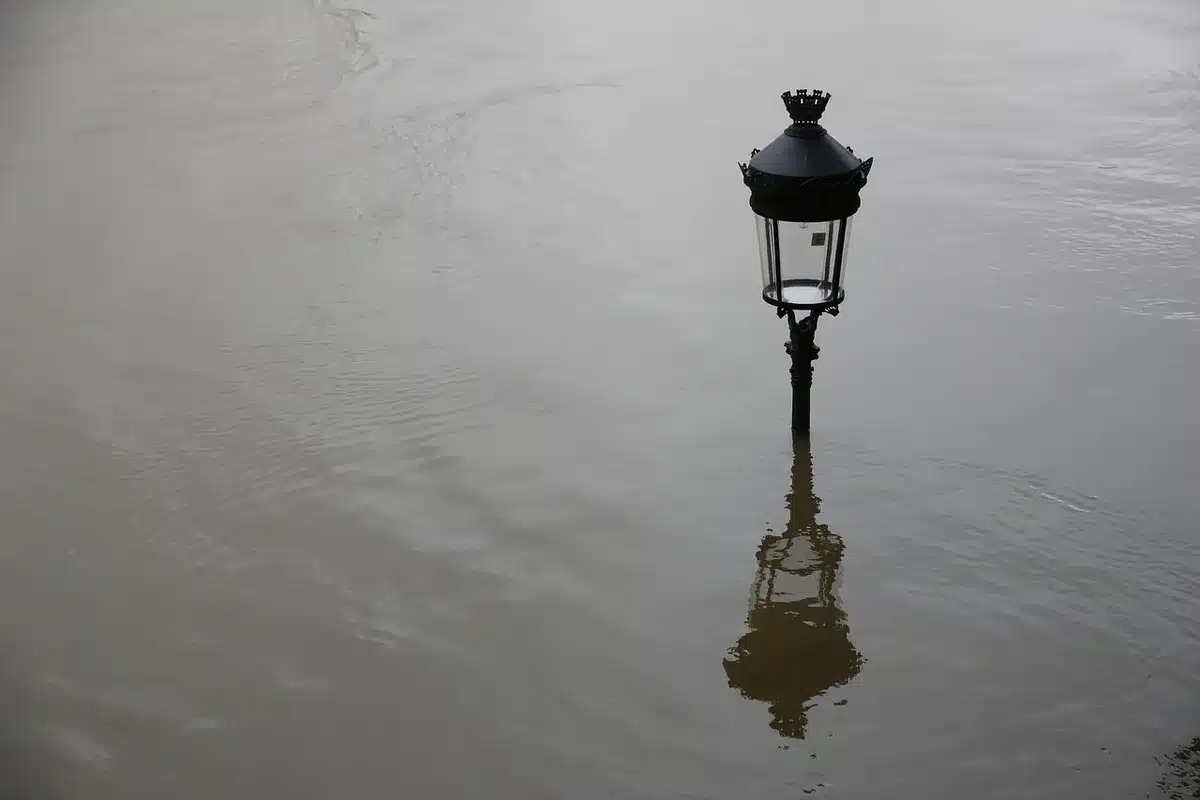 Río desbordado con agua y lodo invadiendo un núcleo rural por la tarde