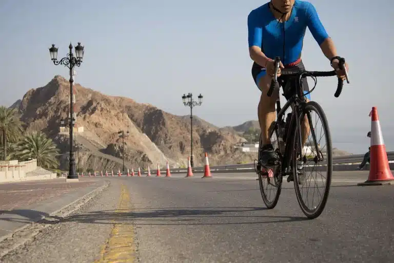 Ciclista joven en kit de equipo profesional ante el pelotón del WorldTour en etapa de montaña
