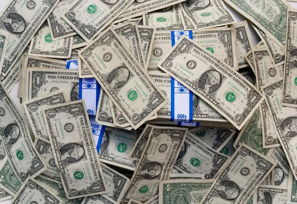 Manos firmando documentos financieros sobre escritorio con gráficos de inversión de fondo