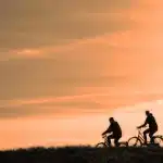 Silueta de un ciclista junto a material y un autobús de equipo, evocando continuidad