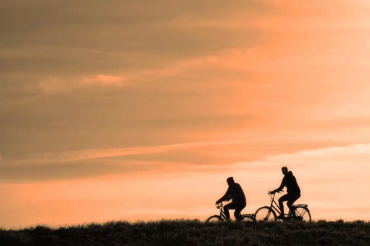 Silueta de un ciclista junto a material y un autobús de equipo, evocando continuidad