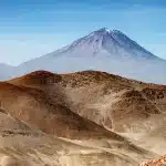 Ciclistas anónimos subiendo por carretera de montaña con calor y paisaje rocoso