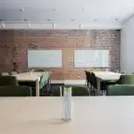 Manos anónimas con kit de robótica y portátil en aula iluminada