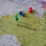 Manos anónimas revisando documentos sobre una mesa con un mapa del mundo desenfocado
